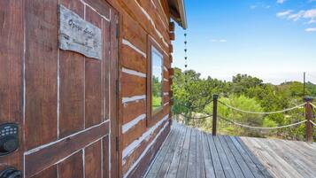 A wooden cabin with a sign reading 'Ozye Lodge' and a wooden deck leading to a scenic view.