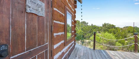 A wooden cabin with a sign reading 'Ozye Lodge' and a wooden deck leading to a scenic view.