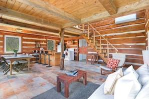 A log cabin interior with a dining area, kitchen, and a staircase.