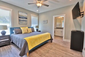 A bedroom with a bed, bedside tables, a ceiling fan, and a TV mounted on the wall. - Canyon Lake Getaway | Private Hot Tub, Fire Pit, Game Room & Near River (Fischer)