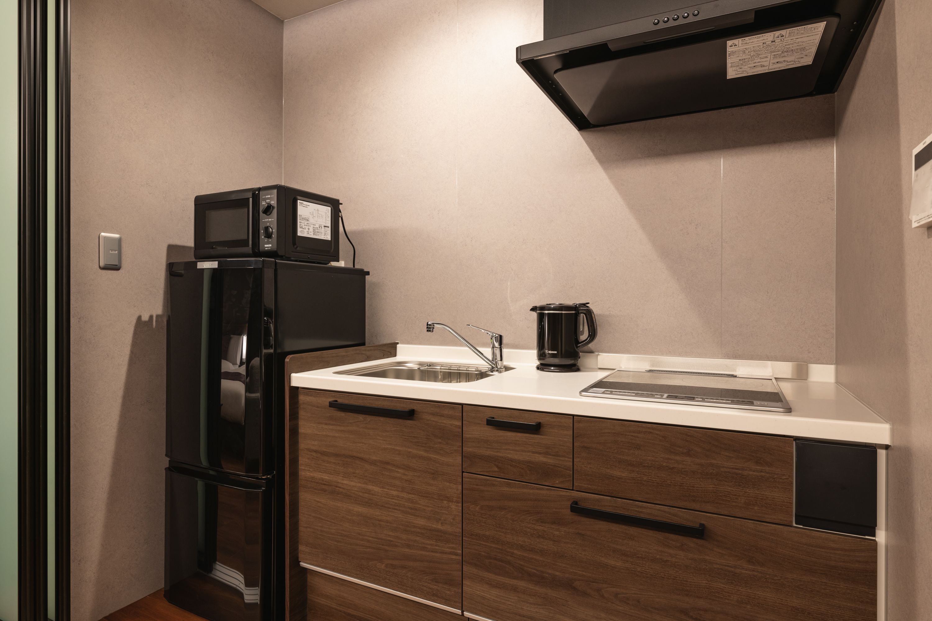 A compact kitchen with a built-in microwave, a coffee maker, and a refrigerator.