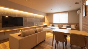 A modern hotel room with a sofa, dining table, and chairs. - GRAND BASE Iolani (Beppu)