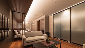 A modern living room with a sofa, a coffee table, and a sliding door. - GRAND BASE Iolani (Beppu)