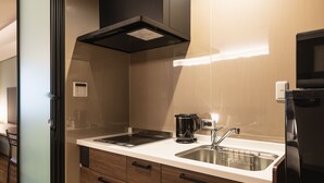 A modern kitchen with a stainless steel sink, a coffee maker, and a built-in oven. - GRAND BASE Iolani (Beppu)