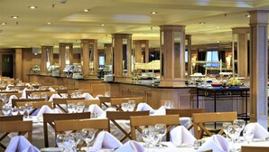 Un salón de banquetes con mesas dispuestas para cenar, que incluye una zona de bufé con diferentes opciones de comida.