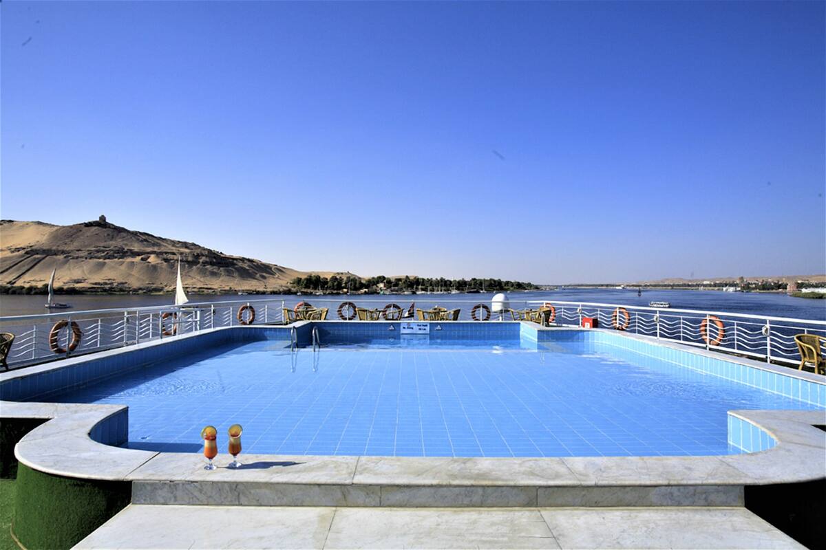 Une piscine avec vue sur une étendue d’eau et une colline en arrière-plan.