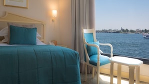 Quarto de hotel com uma cama, uma cadeira, uma mesa e vista para o mar.