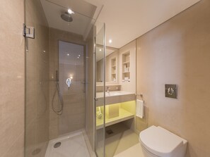 A modern bathroom with a glass-enclosed shower, a toilet, and a sink with a mirror above it.