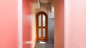 A narrow hallway with a wooden door featuring a frosted glass panel and a letter 'A' above it. - Simple Stay Makishi (Naha)