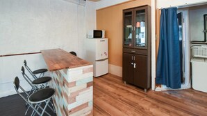 A compact kitchen with a wooden counter, a refrigerator, and a cabinet. - Simple Stay Makishi (Naha)