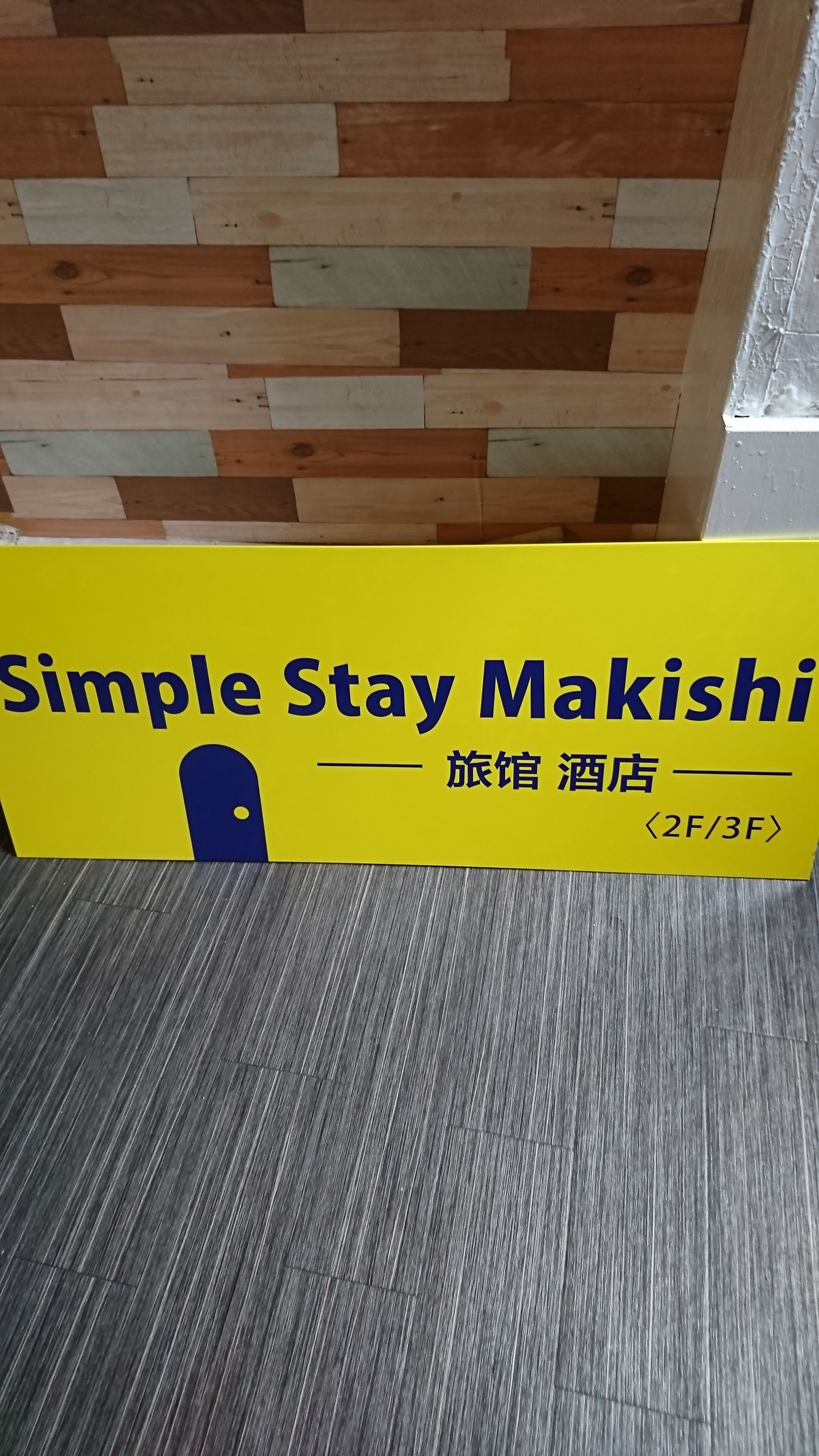 A yellow sign with "Simple Stay Makishi" and "旅館 酒店" text, indicating a hotel.