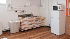 A compact kitchen with a wooden backsplash, a sink, a refrigerator, and a microwave. - Simple Stay Makishi (Naha)