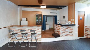 A kitchen with a bar area, a refrigerator, and a microwave. There are two bar stools and a sink with a faucet. - Simple Stay Makishi (Naha)
