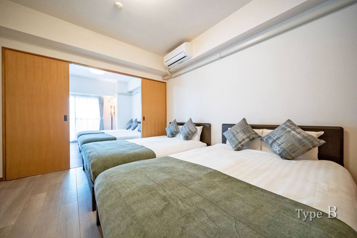Habitación de hotel con dos camas, un armario de madera y un equipo de aire acondicionado.