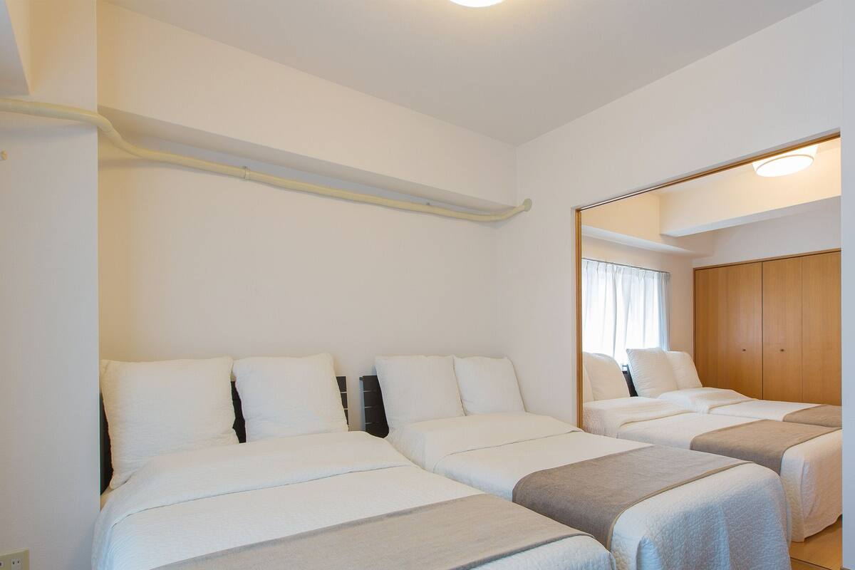 Una habitación con dos camas, un armario de madera y un espejo.