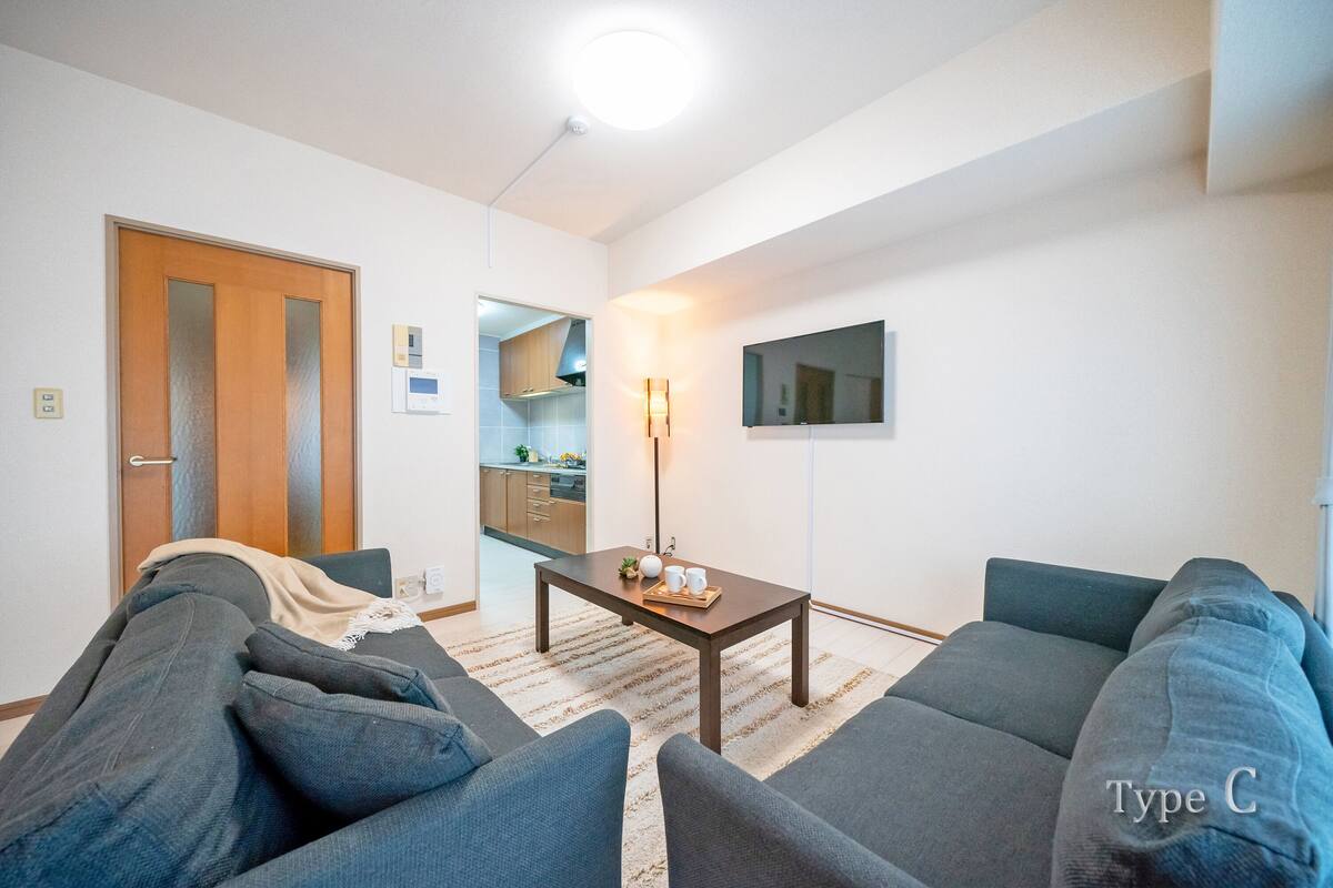 Una sala de estar con sofá, mesa de centro y televisor en la pared.
