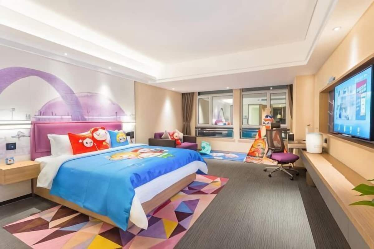 Una habitación de hotel con una cama, un escritorio, un televisor y una ventana.