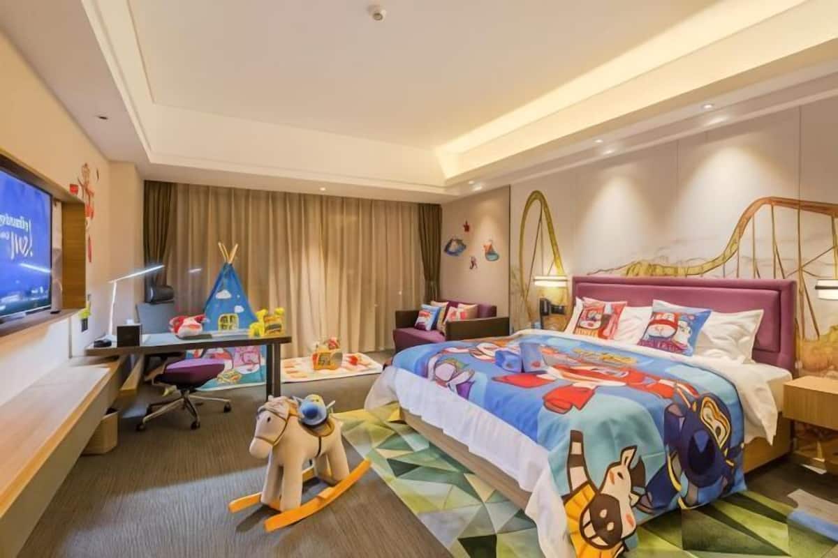 Habitación de hotel con cama, escritorio, silla y televisor.
