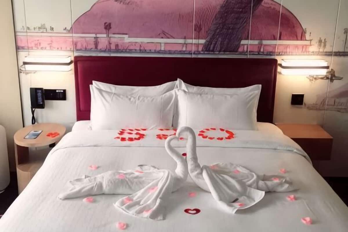 Habitación de hotel con cama, almohadas, cabecero y un muro con un mural.
