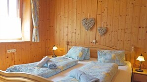 Una stanza in legno con un letto, due comodini e due decorazioni a forma di cuore.
