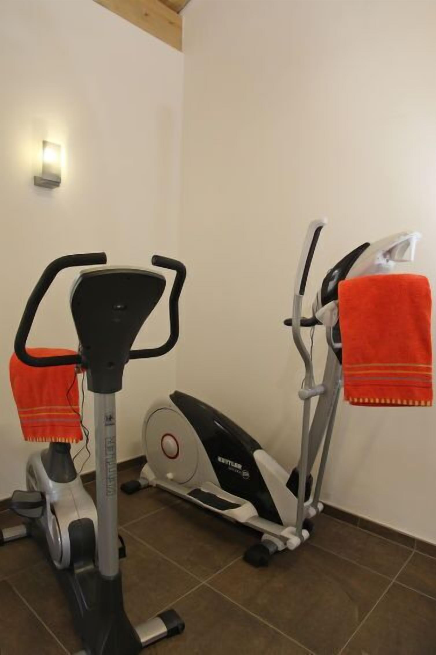 Una palestra domestica con una ellittica e una cyclette, entrambe con degli asciugamani sopra.