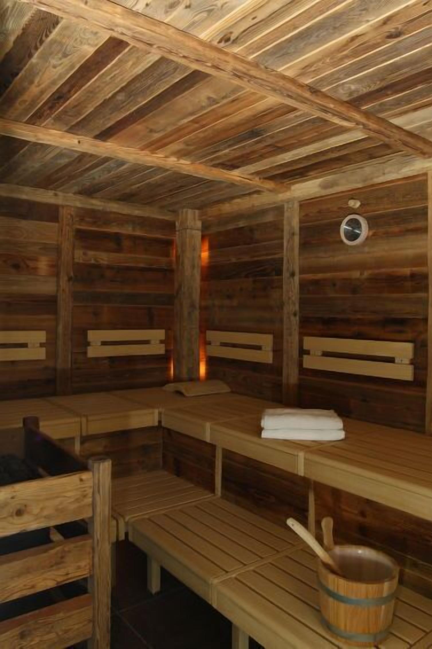 A wooden sauna with benches and a wooden bucket.