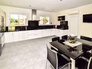 A modern kitchen with white cabinets, black countertops, and a dining area with a black table and chairs.