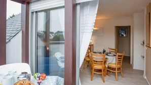 A balcony with a table set for two, a basket of bread, and a fruit bowl. - Bleue Océane by Interhome (Carnac)