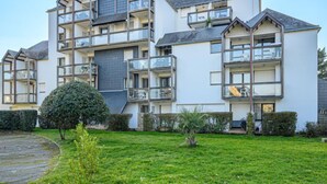 A multi-story residential building with balconies, a central courtyard, and a well-maintained lawn. - Bleue Océane by Interhome (Carnac)