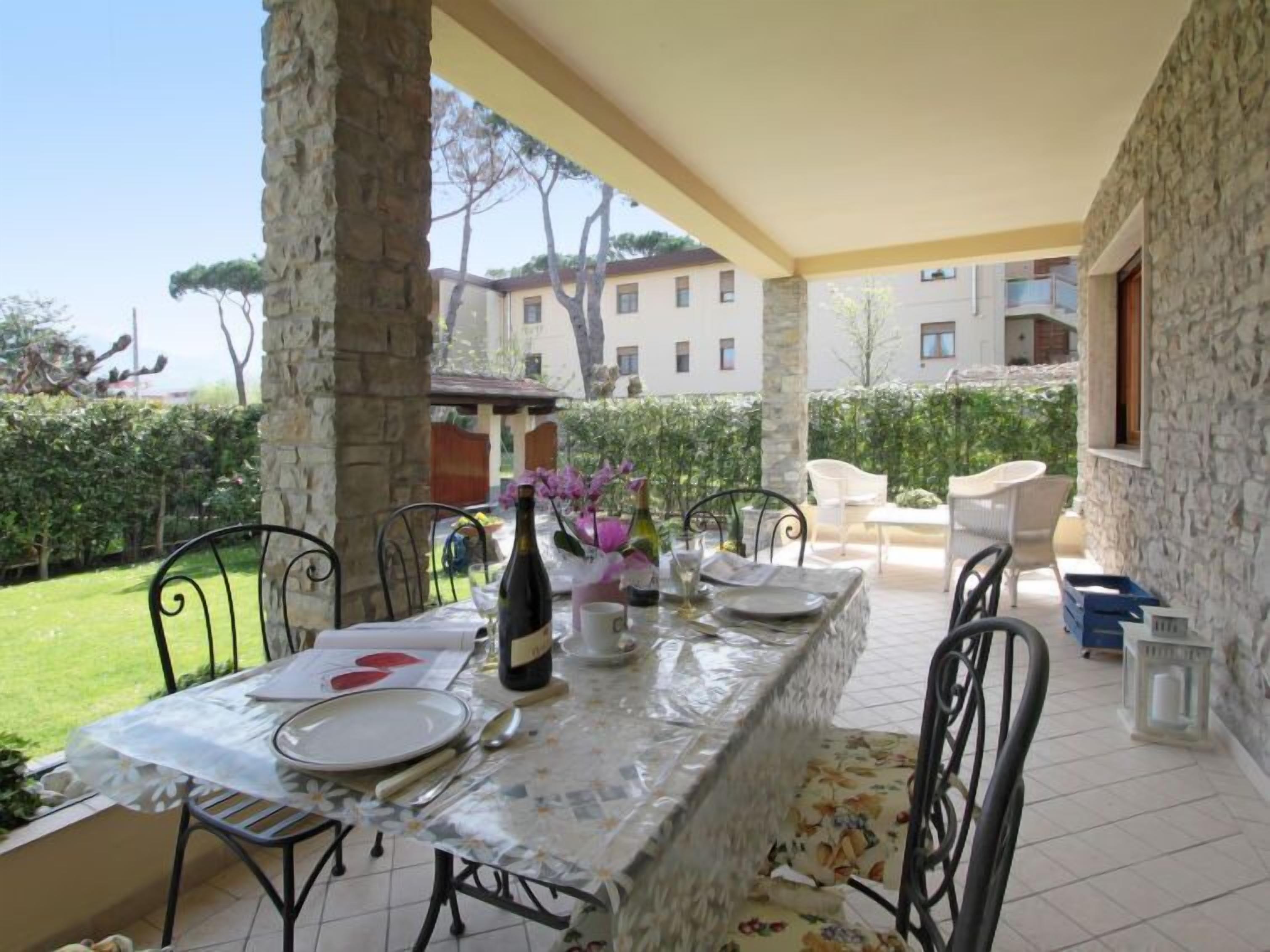 Un patio al aire libre con una mesa lista para comer, rodeado de muros de piedra y vistas a edificios en el fondo.