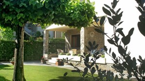 Ein Haus mit überdachter Terrasse, Steinmauern und einem gepflegten Rasen.