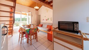 Una cocina acogedora con vigas de madera, una mesa de comedor con sillas, microondas y sofá.
