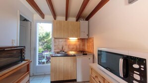 Una cocina compacta con armarios de madera, un microondas y una pequeña isla con un lavamanos.
