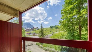 Un balcon offrant une vue dégagée sur un paysage montagneux, une cabane en bois et un banc.