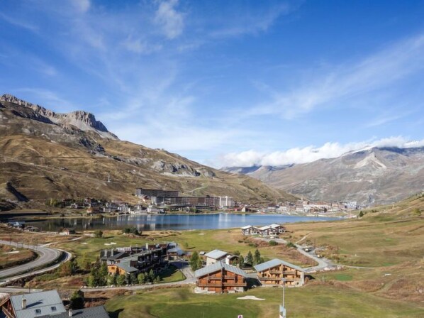 A mountainous landscape with a lake, buildings, and a road.