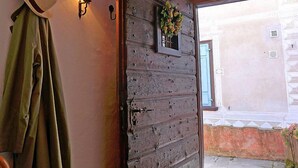 Une porte en bois rustique avec une plaque numérotée, un porte-chapeau fixé au mur et une applique murale.
