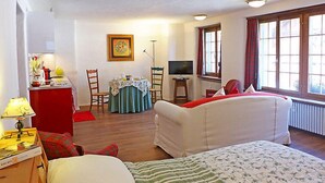 Une chambre avec deux lits, une table à manger, un téléviseur et une fenêtre avec des rideaux.