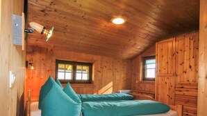 A wooden cabin room with a bed, a window, and a ceiling light. - Auhäusl by Interhome (Fügen)