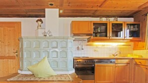 A kitchen with wooden cabinets, a stove, and a sink. - Auhäusl by Interhome (Fügen)