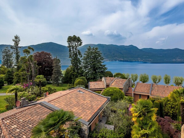 Un barrio residencial con techos de tejas de terracota, abundante vegetación y un lago al fondo.