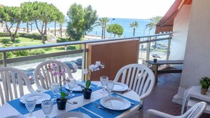 A dining table set with white chairs, plates, and cutlery, overlooking a scenic view of the sea and greenery. - La Pinède by Interhome (Cagnes-sur-Mer)