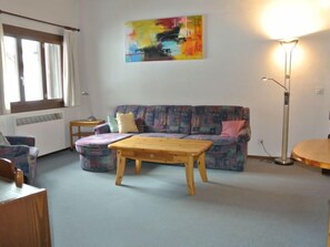 Un salon avec un canapé, une table basse en bois, un lampadaire et un tableau accroché au mur.