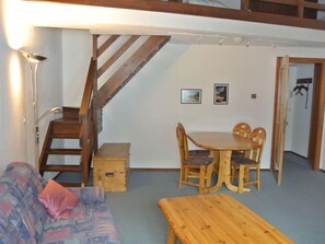 Une pièce chaleureuse avec un escalier en bois, une table à manger avec des chaises, un canapé et un banc en bois.