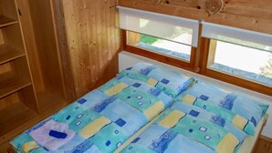 Ein Holzhüttenraum mit einem Bett, einem Fenster und einem Holzschrank.