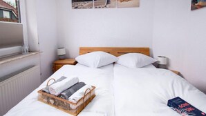 Quarto de hotel com cama, mesa de cabeceira, luminária, janela e obras de arte nas paredes.