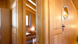 A wooden interior with a bed, a nightstand, and a window with curtains. - Miranda by Interhome (Champex)