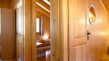Ein Zimmer mit Holzausstattung, einem Bett, einem Nachttisch und einem Fenster mit Vorhängen.