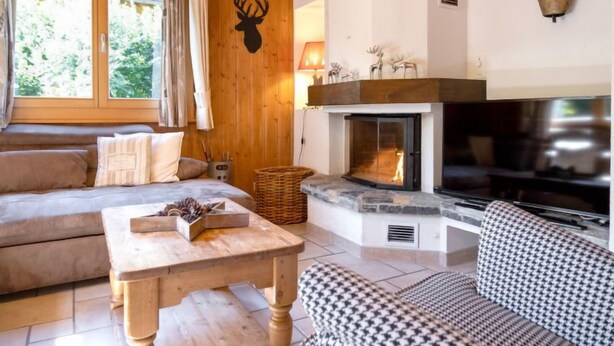 A cozy living room with a fireplace, wooden walls, and a sofa. - Miranda by Interhome (Champex)