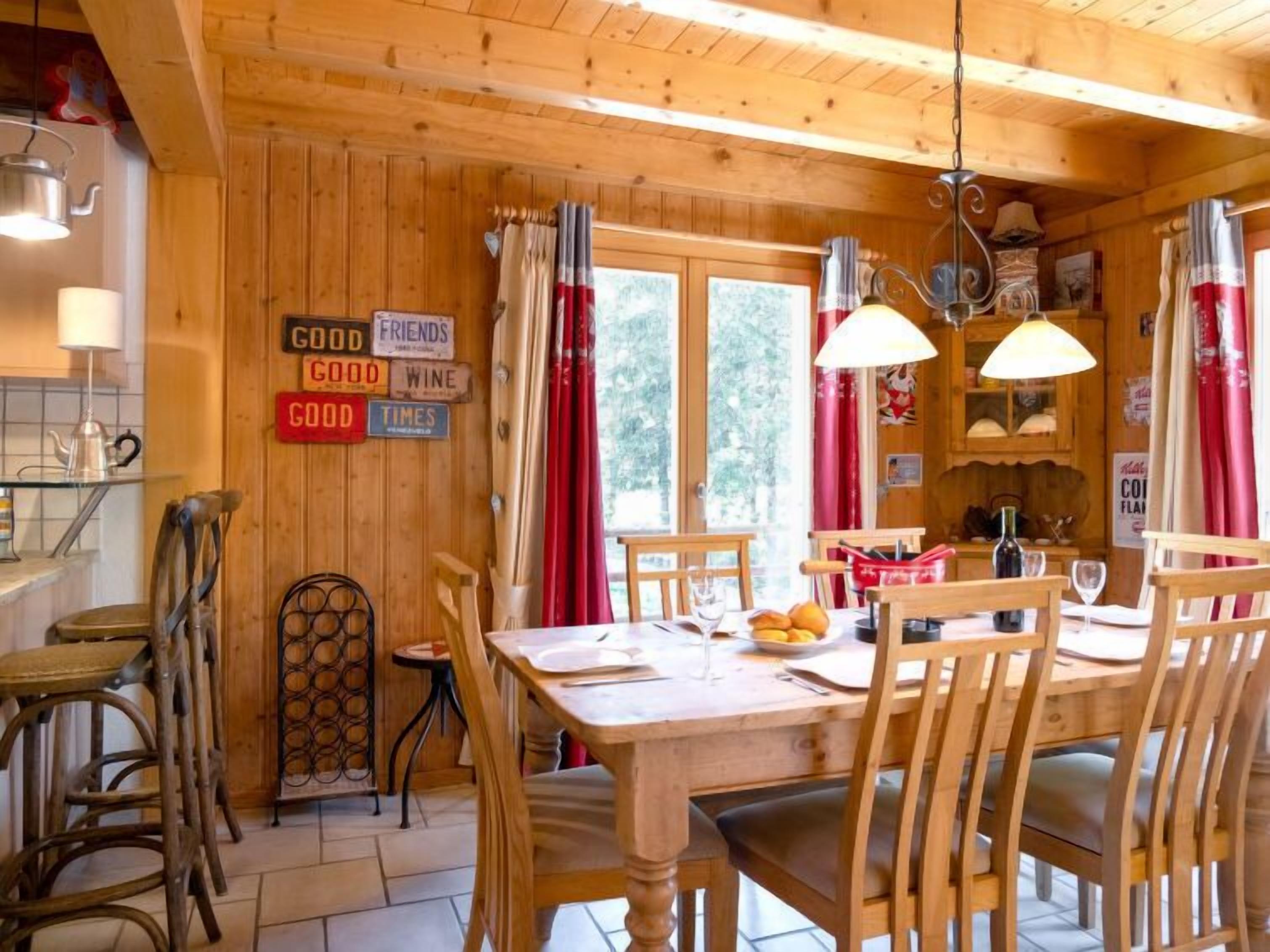 A wooden interior with a dining table, chairs, and a kitchen area.