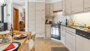 Cozinha moderna com armários de madeira clara, forno embutido e máquina de lavar louça.